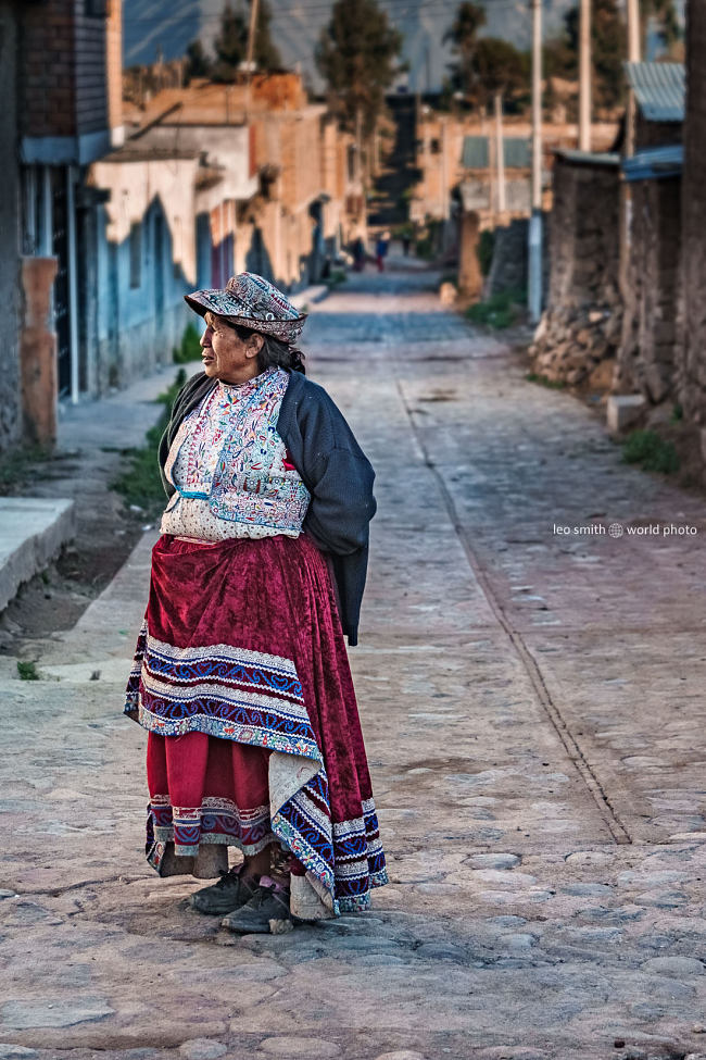 Leo Smith World Photo: Peru Photos and Prints - A lady in traditional clothing stands at the top of a narrow street, Cabanaconde, Peru