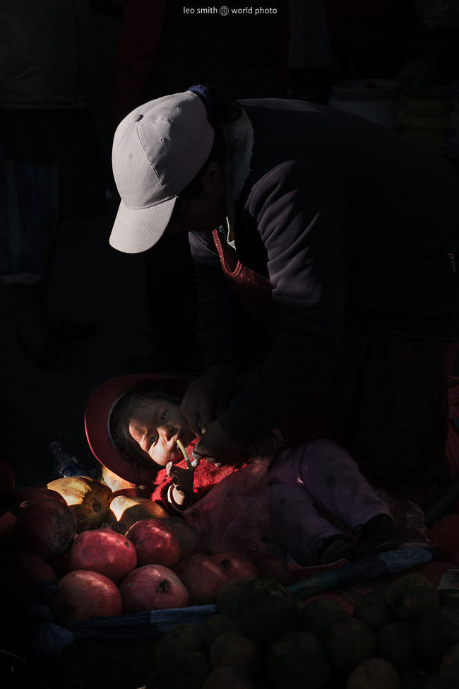 Leo Smith World Photo: Peru Photos and Prints - A baby lies across some apples of her mother's market stall, Cucso, Peru