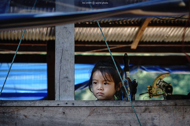 A young girl stands on the deck of a river boat on the Mekhong River, Laos