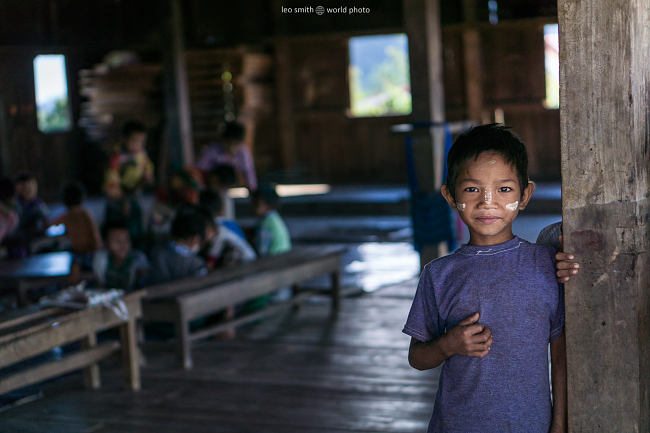 A boy stands at the entrance to the school house of a small hilltribe village, Shan State, Myanmar (Burma)