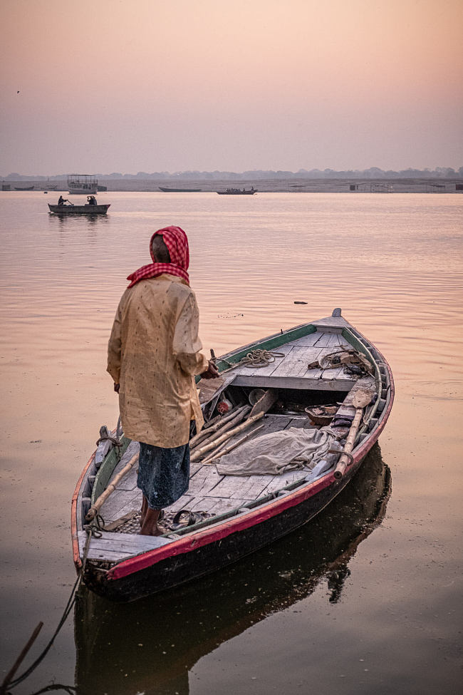 A man stands in his boat on the River Ganga (Ganges), Varanasi, India - photo by Leo Smith Photo Video